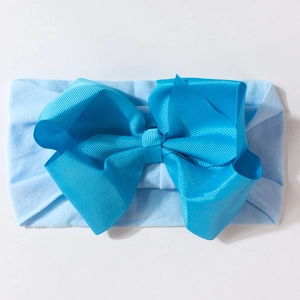 Detail of baby headband with a large royal blue ribbed grosgrain bow on elastic band