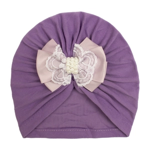 Detail of baby turban hat with layered purple bow, white lace and pearl embellishments