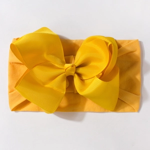 Bright yellow stretchy baby headband with a large grosgrain ribbon bow on white background