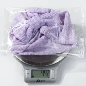 Purple knitted baby turban with bow detail on a scale weighing 44.2 grams