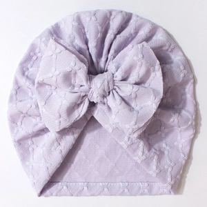 Detail of lavender baby beanie featuring jacquard texture and a large decorative bow