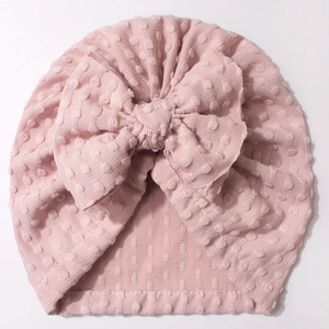 Pink newborn baby hat with large bow and embossed dot texture for infants and toddlers