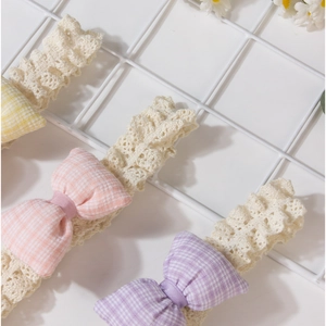 Detail von Baby-Spitzenstirnbändern mit karierten Schleifen in Rosa, Lila und Gelb