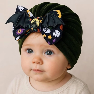 Détail du bonnet d'Halloween pour bébé en vert foncé avec un nœud festif et des chauves-souris