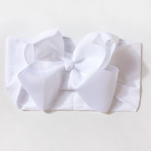 Detail showing the ribbed fabric texture of a pure white oversized baby bow headband