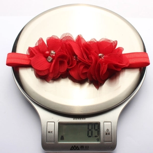 Dettaglio della fascia per capelli con fiori in chiffon rosso e perle su bilancia da 8.9g