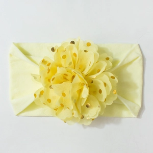 Détail d'un bandeau bébé jaune pâle avec ornement floral à pois dorés scintillants