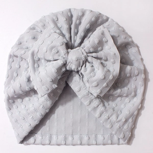 Detail of light gray baby beanie with dotted texture knit and large bow embellishment