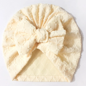 Detailed view of cream beige baby beanie with soft knitted heart jacquard and large bow