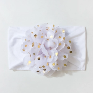 Détail du bandeau bébé avec fleur en mousseline blanche et pois dorés brillants