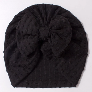 Detailed view of black textured knit baby turban hat with a large decorative bow