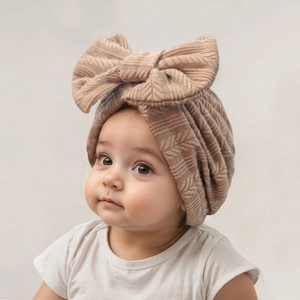 Détail d'un bonnet pour bébé en maille douce avec texture épi et grand nœud décoratif