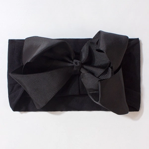 Detailed close-up of a large black textured bow headband for babies and children