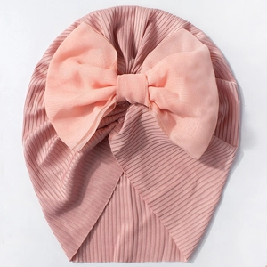 Détail du turban rose pour bébé en tissu côtelé avec un grand nœud en mousseline