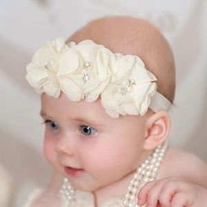 Dettaglio di fiori in chiffon crema con perle e strass su una fascia per neonati
