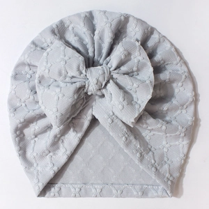 Detailed view of light blue baby hat with jacquard texture and big bow detail