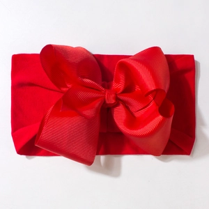 Detailed close-up of vibrant red baby headband with a large textured grosgrain ribbon bow