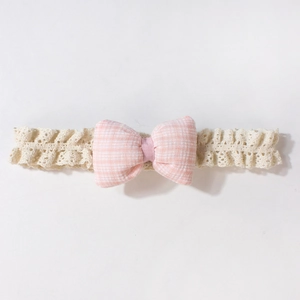 Detailansicht eines Baby-Stirnbands mit rosa karierter Schleife und beiger Spitze