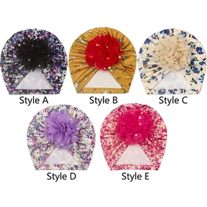 Détail de cinq turbans pour bébé avec de grandes fleurs en résille et des paillettes dorées