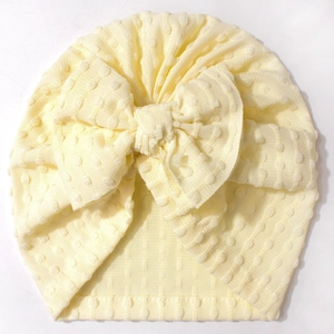 Close-up of baby turban hat featuring a textured polka dot bow and breathable knit fabric
