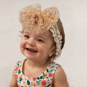 Detail view of baby lace headband featuring a large gold mesh floral bow for newborns