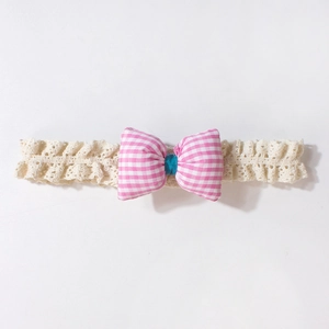 Detail eines Baby-Spitzenstirnbands mit rosa karierter Schleife auf weißem Hintergrund