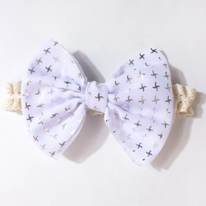 Vue détaillée du bandeau bébé en dentelle avec nœud blanc à motifs d'étoiles