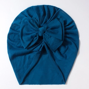 Detailed view of peacock blue baby turban hat with a large bow made of soft ribbed knit cotton