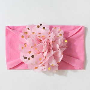Détail d'un bandeau bébé élastique avec grande fleur en maille rose et pois dorés