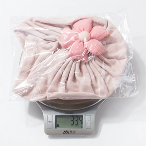 Detailed view of pink floral baby turban hat being weighed on a digital scale