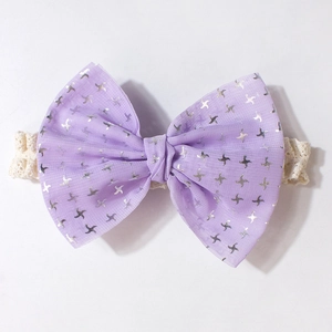 Détail du bandeau bébé avec nœud en maille violette et étoiles argentées sur dentelle