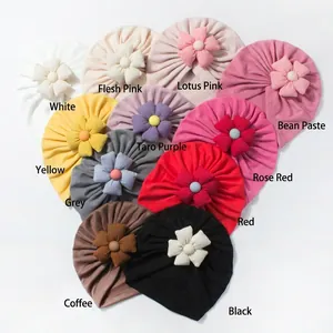 Flat lay of colorful baby turban hats with floral knots arranged in a heart shape