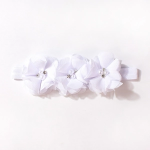 Dettaglio di tre fiori in chiffon bianco con perle e strass sulla fascia per neonata