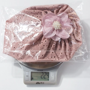Rosa Baby-Turbanmütze mit 3D-Organzablüte beim Wiegen auf einer digitalen Waage