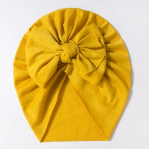 Cute ginger yellow baby hat with a large bow, made of soft elastic knitted cotton fabric