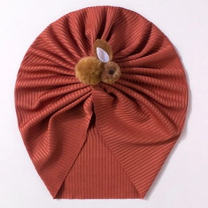 Gros plan du turban pour bébé en maille côtelée brique avec un petit lapin en peluche