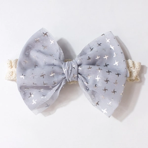 Détail d'un bandeau pour bébé avec dentelle et un nœud bleu orné de motifs d'étoiles