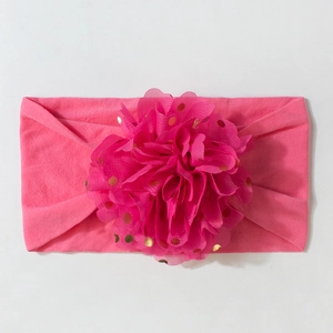Détail d'un bandeau rose pour bébé avec fleur en tulle et pois dorés brillants
