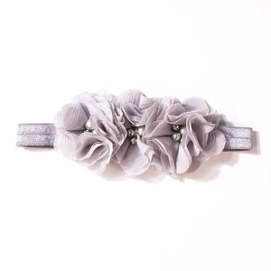 Dettaglio di fiori in chiffon viola chiaro con perle e strass su una fascia per neonati