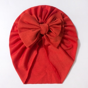 Detail view of the soft red knit texture and large bow on this baby turban hat