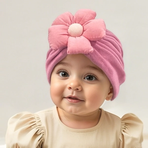 Detail of soft pink baby turban hat featuring a 3D floral decoration on a cute infant