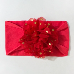 Détail d'un bandeau rouge pour bébé avec une grande fleur à pois dorés scintillants