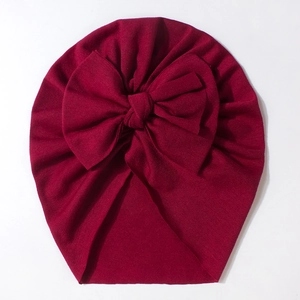 Detailed view of dark red baby turban hat featuring a large knot bow and soft ribbed knit fabric