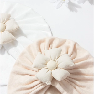 Detailed close-up of soft knitted baby turban hats with 3D fabric flower decorations