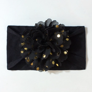 Détail du bandeau pour bébé avec décoration florale en mousseline noire à pois dorés