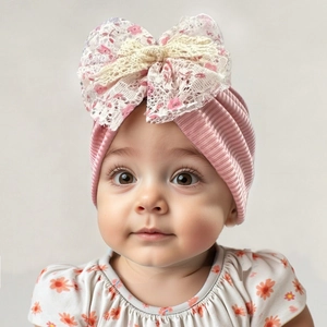 Détail du bonnet turban pour bébé en tricot côtelé rose avec grand nœud en dentelle
