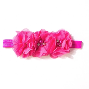 Dettaglio fascia neonata con fiori di chiffon rosa, perle e strass lucidi