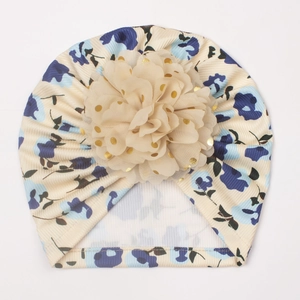 Détail du bonnet turban beige pour bébé avec une grande fleur en mousseline à pois dorés