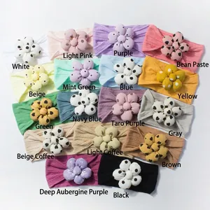 Macro detail of soft knitted baby headbands featuring colorful polka dot 3D floral patterns