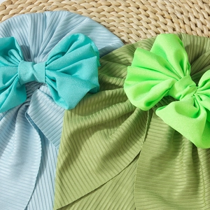 Detailed texture of ribbed knit baby turban hats with large bows in blue and olive colors